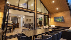 A spacious living area with a large wooden ceiling, a dining table, and comfortable seating.