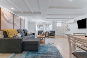 A modern living room with a sectional sofa, a coffee table, and a dining area with a wooden table and chairs.