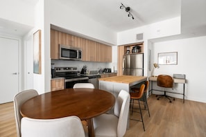 Kitchen features a central island with a sink, range hood, microwave and oven, and a large refrigerator.