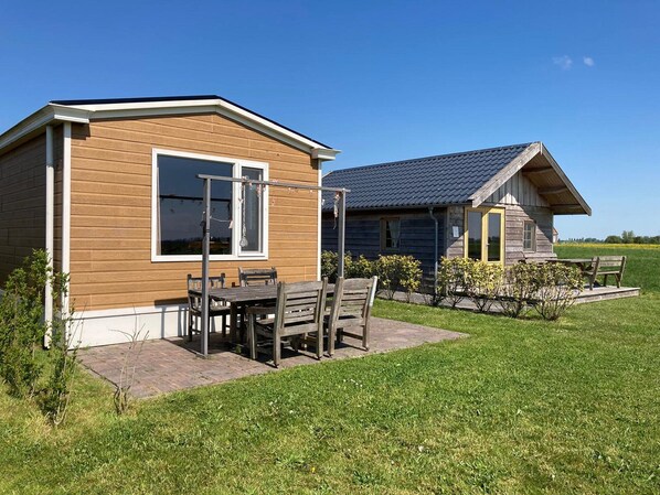 A wooden cabin with a patio and a small garden. - Cottages in Friesland With Farm Experience (Tjerkgaast)