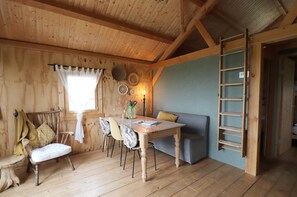 Et interiør af en træhytte med spisebord, stole, bænk, sofa og en stige.