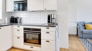 A modern kitchen with white cabinetry, a built-in oven, a microwave, and a coffee maker. - Modern Holiday Haven in Laeso (Læsø)