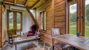 A wooden cabin with a stone floor, a wooden table, and two chairs. - Experience a Regenerative Farm in a New Tiny Home (Nixa)