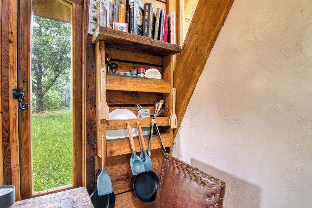 A wooden shelf with books and kitchen utensils.