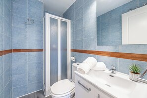 A bathroom with blue tiles, a white toilet, a shower enclosure, a sink with a mirror, and a small potted plant. - Brisa Marina luxury apart in fuengirola near the beach (Fuengirola)