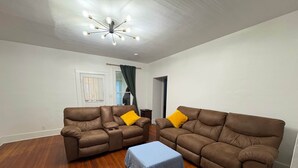 A living room with two brown leather sofas, a small table, and a ceiling light fixture. - Charming 1900 home with furnished kitchen and king bed (Lake Mills)