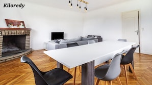A modern living room with a fireplace, a dining table with chairs, a sofa, and a television.