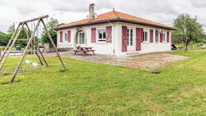 A house with a red-tiled roof, a picnic table, and a swing set in the yard.