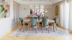 A dining area with a marble table, six chairs, a chandelier, and a large abstract painting. - VESTA - Nile Zamalek Residence (Cairo)