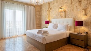 A large bed with white linens and a headboard, two bedside lamps, and a wooden nightstand. - VESTA - Nile Zamalek Residence (Cairo)
