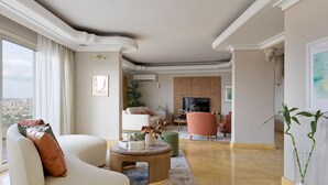 A modern living room with a sofa, coffee table, and a TV in the background. - VESTA - Nile Zamalek Residence (Cairo)