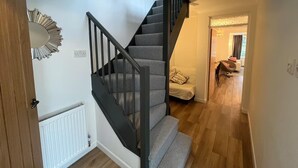 Eine Treppe mit grauen Teppichstufen und schwarzen Geländern, die zu einem Raum mit einem weißen Heizkörper und einer Holztür führt.