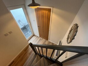 A staircase leading to a wooden door with a view of a balcony.