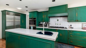 Una cocina con armarios color aguamarina, un refrigerador de acero inoxidable, un horno empotrado y una estufa a gas.