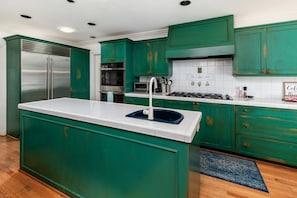 A kitchen with teal cabinetry, a stainless steel refrigerator, a built-in oven, and a gas stove. - La Jolla Retreat: Pool, Tennis, & Walk to Beach (San Diego)