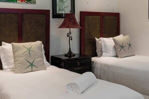 A hotel room with two beds, a nightstand, a lamp, and a framed picture on the wall.