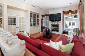 A living room with a red sofa, a glass coffee table, and a fireplace.