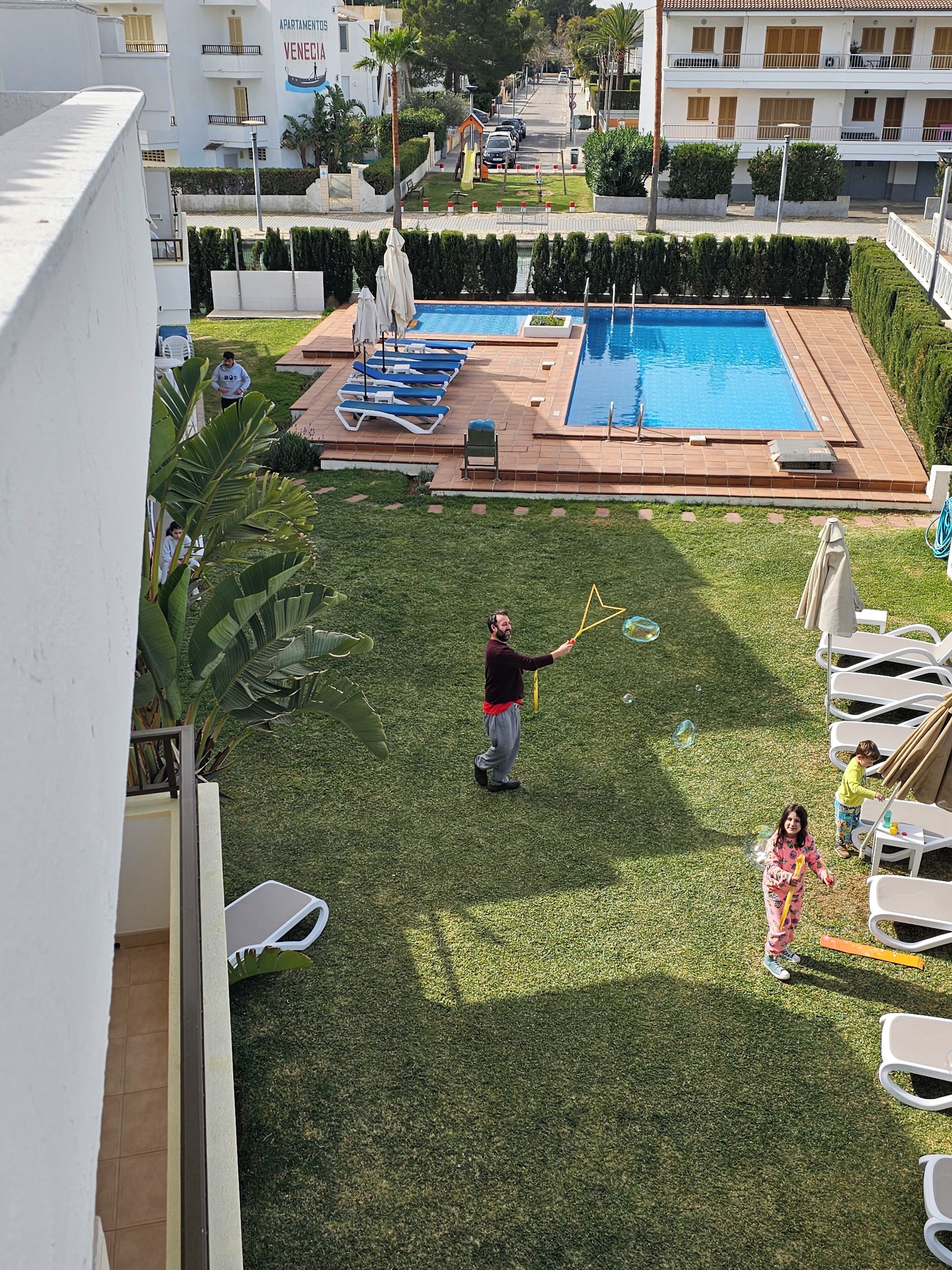A residential area with a swimming pool, lounge chairs, and a well-maintained lawn.