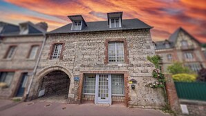 Un bâtiment en pierre doté d’une entrée centrale en arc de cercle, d’un petit porche et d’une boîte aux lettres.