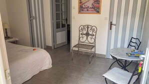 Une chambre à coucher avec un lit, une chaise, une petite table et une affiche accrochée au mur.