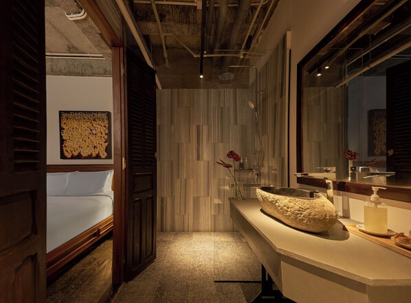 A modern bathroom with a large mirror, a stone sink, and a shower. - Anima - Vietnamese Contemporary Art Boutique Hotel (Ho Chi Minh City)