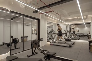 A gym with treadmills, a rowing machine, and weightlifting equipment. - Anima - Vietnamese Contemporary Art Boutique Hotel (Ho Chi Minh City)