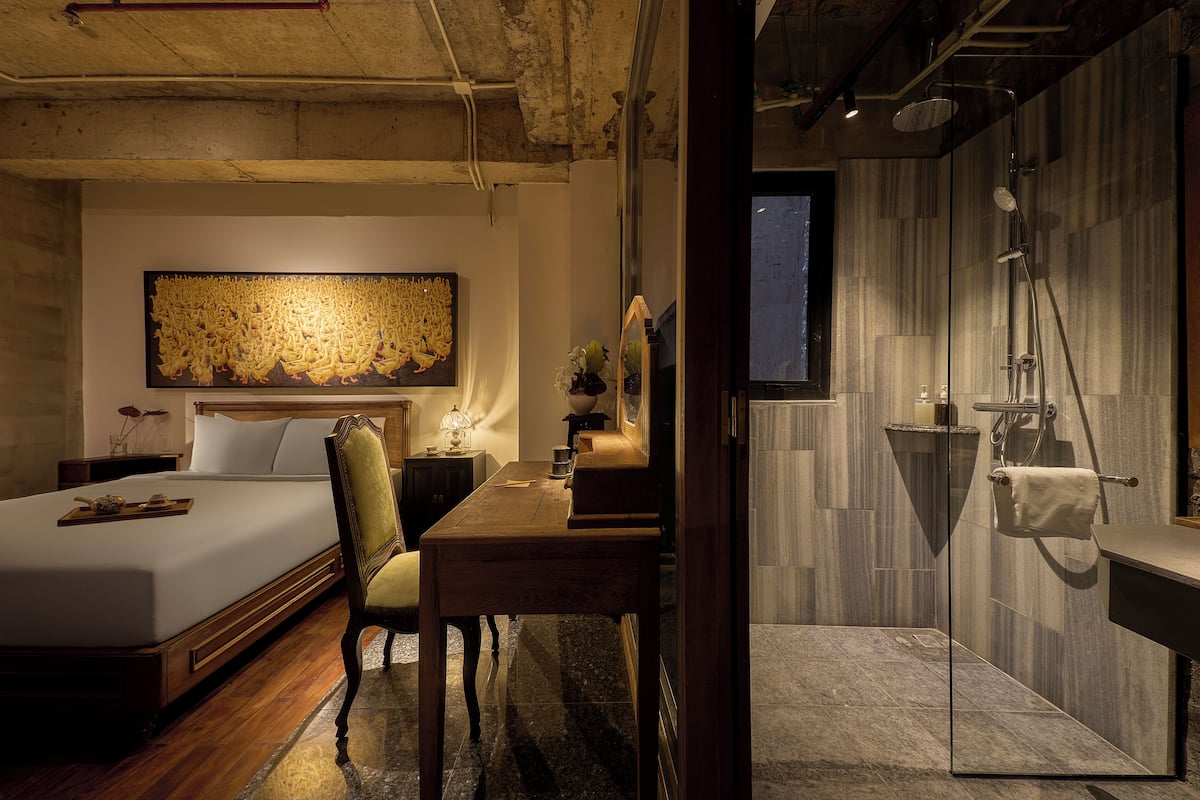 A modern hotel room with a large bed, a desk, and a shower area.
