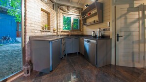 A compact kitchen with a built-in dishwasher, a window with a view of greenery, and a bicycle parked outside. - Junior Garden Villa (Sapanca)