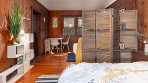 A bedroom with wooden walls, a skylight, a bed, a desk, and a chair. - Downtown Studio Garden Cottage | Near UC + Parking (Berkeley)