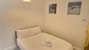 Un dormitorio con una cama, una lámpara colgante y dos cuadros en la pared.