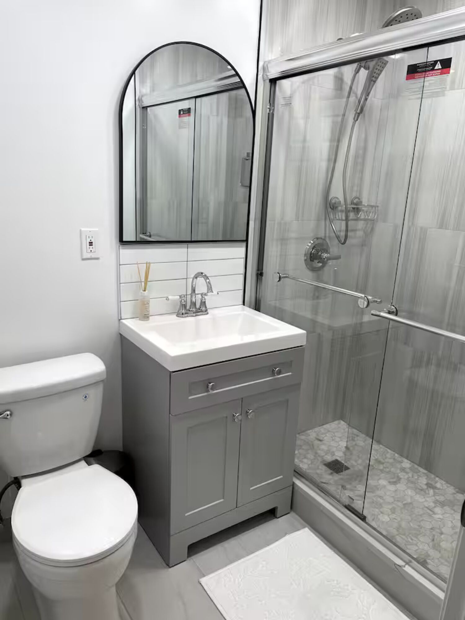 Une salle de bain équipée de toilettes, d’un lavabo, d’un miroir et d’une douche.
