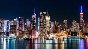 A nighttime cityscape with illuminated skyscrapers and a body of water reflecting the lights. - WORLD CUP + minutes to NYC (Union City)