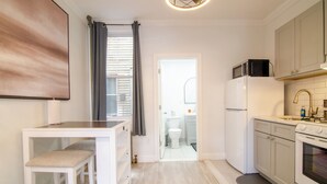 A compact kitchen with white cabinetry, a built-in oven, and a microwave. - WORLD CUP + minutes to NYC (Union City)