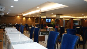 Un restaurante con varias mesas y sillas, una pantalla de televisión y una zona de bar.
