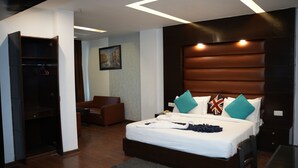 Una habitación de hotel moderna con una cama grande, un armario, una zona de estar y un cuadro en la pared.