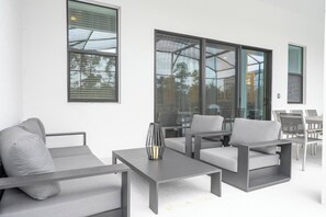 A modern outdoor seating area with a sofa, armchairs, and a table. - Luxury Home | BEST Resort Near Disney (6067PG) (Orlando)