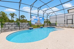 An indoor swimming pool with a castle mural, lounge chairs, and a stone wall.