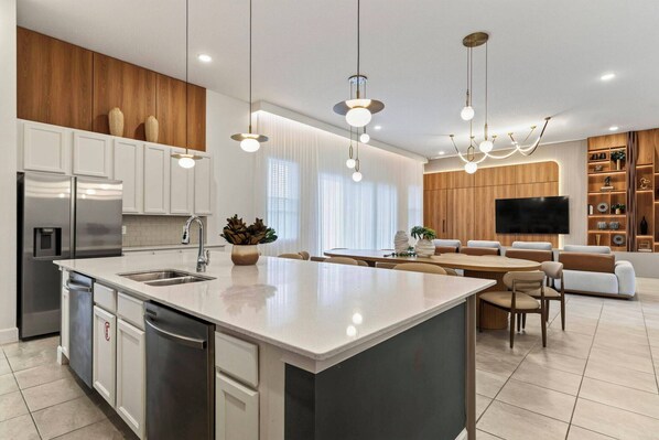 A modern kitchen with a central island, stainless steel appliances, and a dining area with a sofa and chairs.