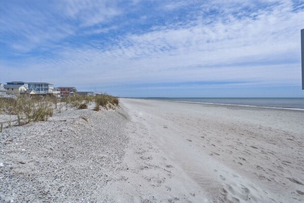 A beach with a row of houses, sandy beach, and a clear sky.