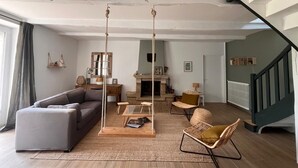 Una sala de estar con sofá, mecedora, una mesita de centro y chimenea.