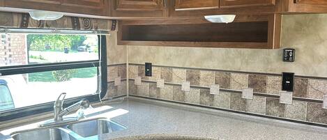 Kitchen area with double sink, oven, and patterned tile backsplash.