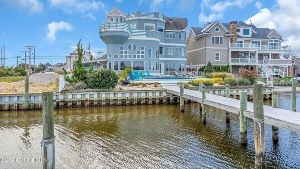 Une propriété située au bord de l’eau, comprenant une grande maison dotée d’une tourelle, d’un quai et d’une piscine.