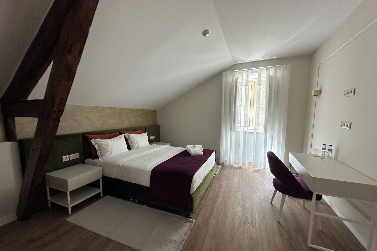 Une chambre à coucher moderne avec un lit, des tables de chevet, un bureau et une chaise.