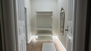 Un couloir avec une porte blanche, un tapis blanc et une étagère blanche.