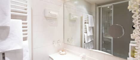 Un baño moderno con un lavamanos blanco, cabina de ducha de vidrio y un perchero para toallas.