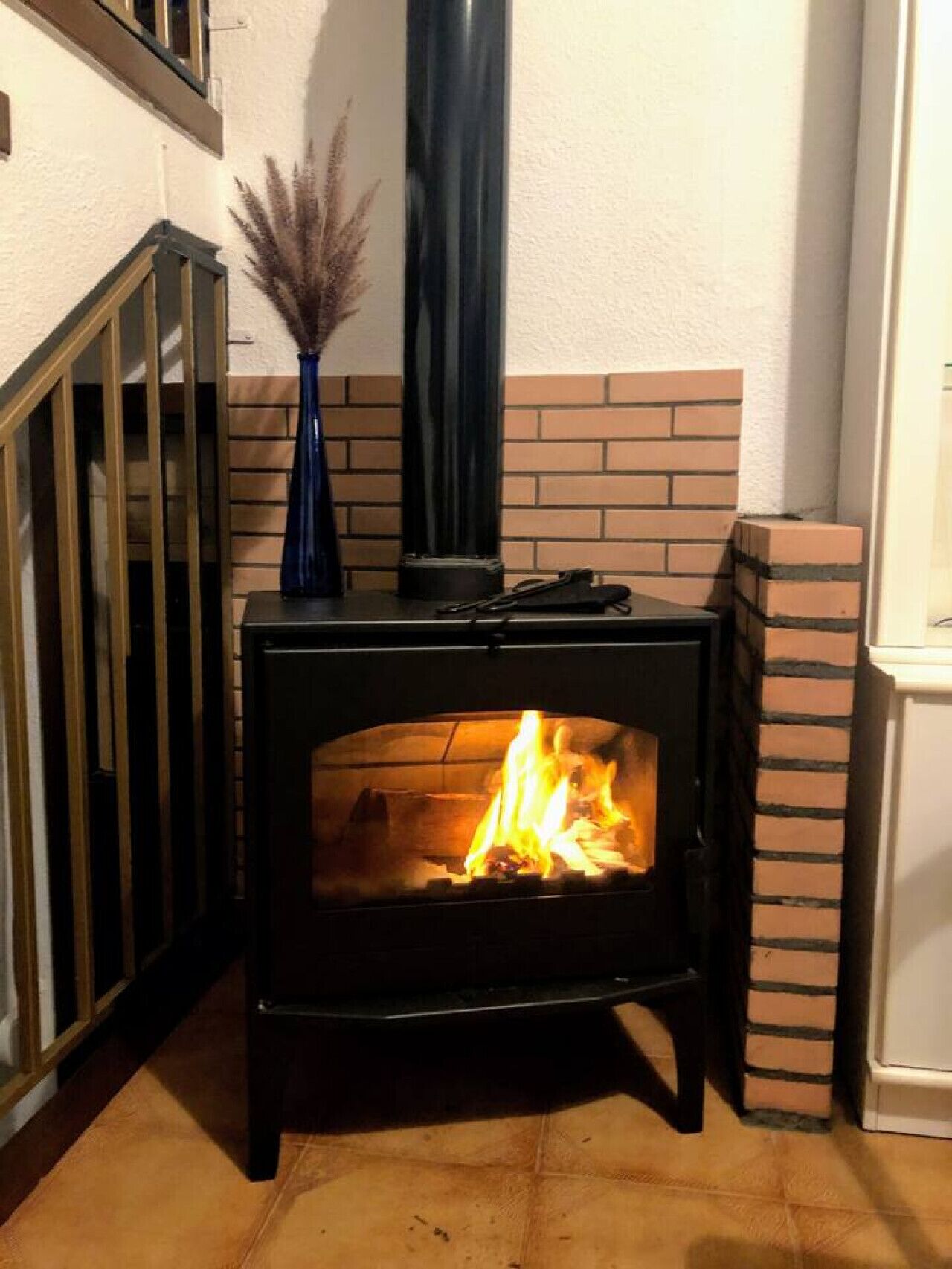 En brændeovn med en murstensvæg og gelænder i træ.