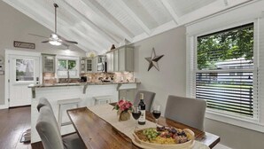 Un comedor con una mesa de madera, sillas, una decoración con estrellas y una ventana con persianas.