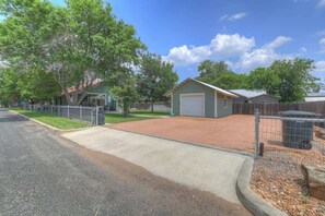 A residential area with a paved driveway, a garage, and a fenced backyard.