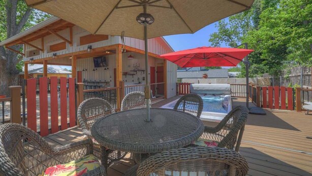 A deck with wicker furniture, a pool, and a covered area with a red umbrella. - Casa Salvia Blanca + Rojo & Tejas Combo! (Fredericksburg)