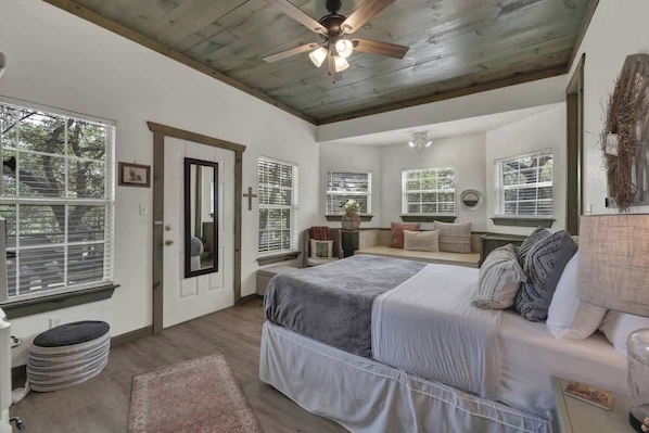A bedroom with a bed, a ceiling fan, a window, and a door.